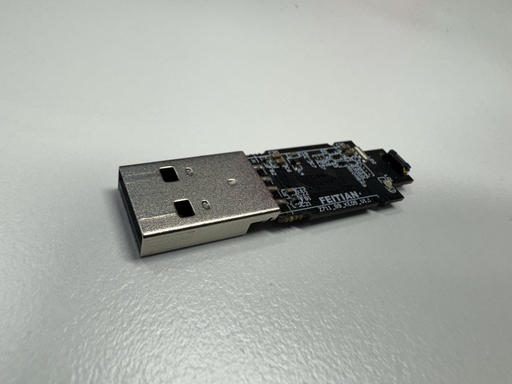 FEITIAN nRF52840 dongle with exposed PCB on a white desk